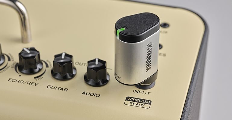 The YW10T with its LED flashing green is plugged into the THR30II Wireless guitar amp on a gray background.