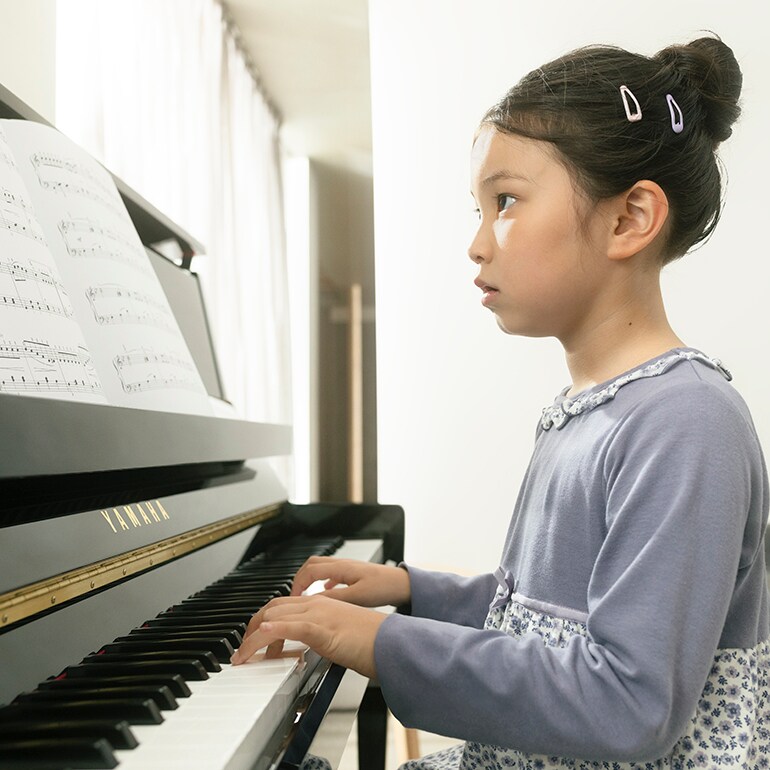 Một đứa trẻ hào hứng chơi đàn piano upright B Series.