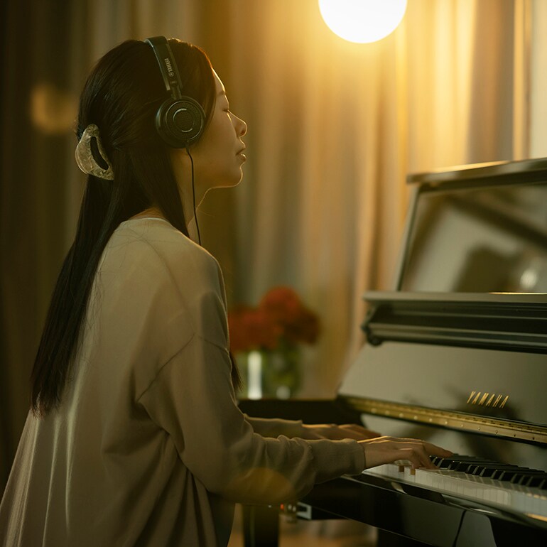 Người phụ nữ tận hưởng không gian luyện đàn hoàn toàn riêng tư với tai nghe.