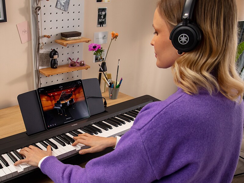 A person using headphones while practicing on the P-143BT