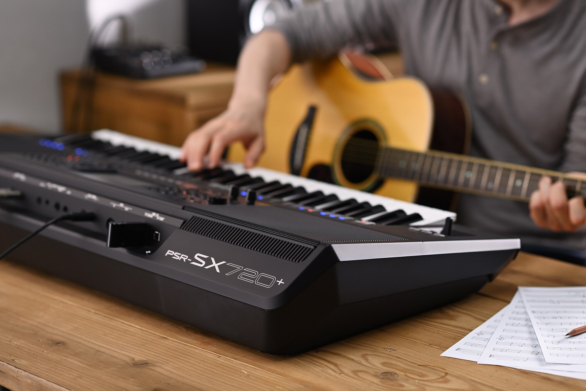 Ảnh chụp một người đang chơi đàn Yamaha Arranger Workstation PSR-SX720+ trong khi cầm đàn guitar.