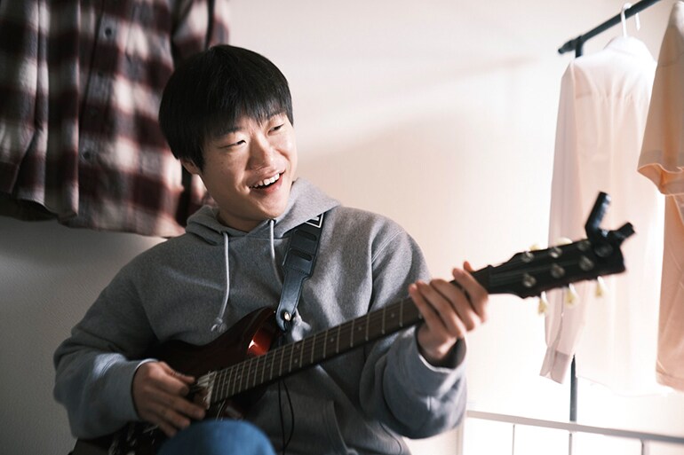 Một người đàn ông đang thử chơi guitar lần đầu