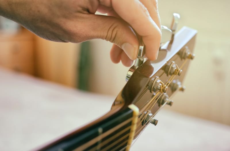 Vặn khóa đàn Guitar Acoustic theo chiều kim đồng hồ để nới lỏng dây đàn